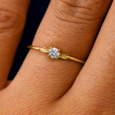 A solid 14k yellow gold Moissanite Gemstone Two Leaf Ring on a model's finger
