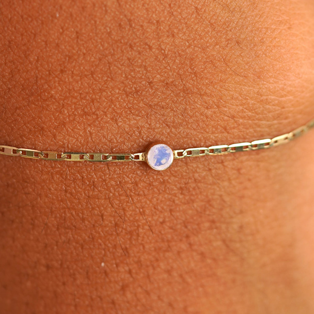 Close up view of a models wrist wearing 14k yellow gold Moonstone Bracelet