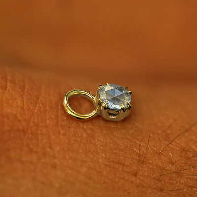A solid yellow gold Salt and Pepper Diamond Charm for earring resting on the back of a model's hand