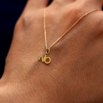 A 14k gold No Charm on a Cable Chain draped over the back of a models hand