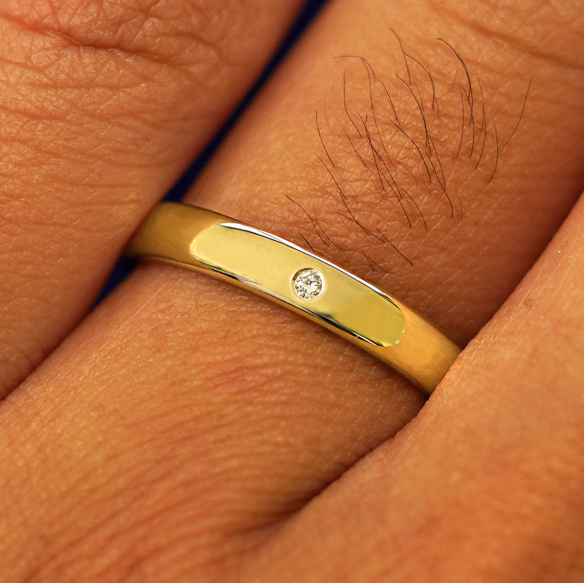 Close up view of a model's fingers wearing a 14k yellow gold Mix Mirror Band with one diamond