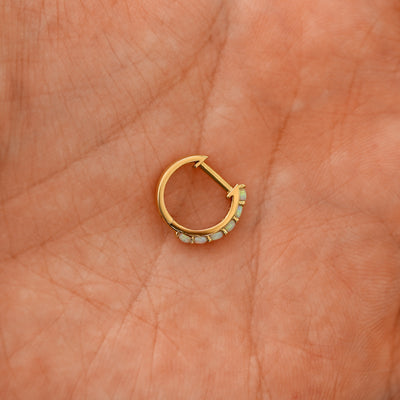 A closed Opal huggie hoop laying in a models palm