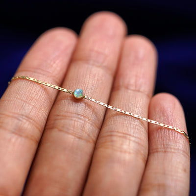 A yellow gold Opal Bracelet resting on a model's fingers