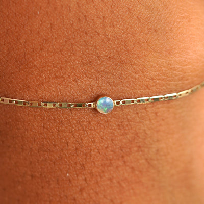 Close up view of a models wrist wearing 14k yellow gold Opal Bracelet