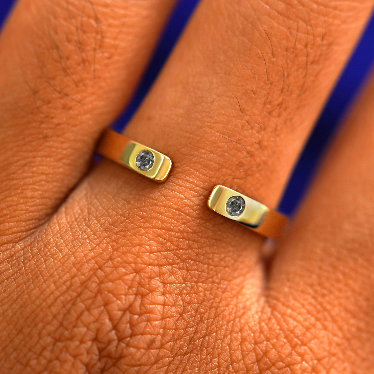 Close up view of a model's fingers wearing a 14k yellow gold Open Industrial Salt and Pepper Band