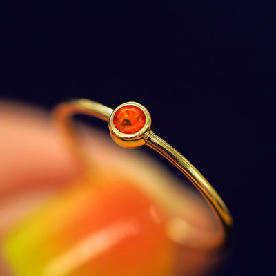 A model holding a Fire Opal Ring tilted to show the details of the bezel setting