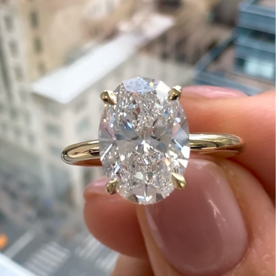 An oval diamond ring in model's hand