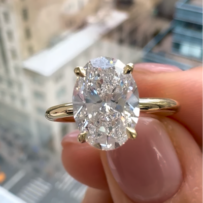 An oval diamond ring in model's hand