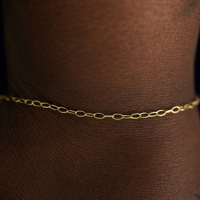 Close up view of a model's wrist wearing a solid yellow gold Veren Bracelet