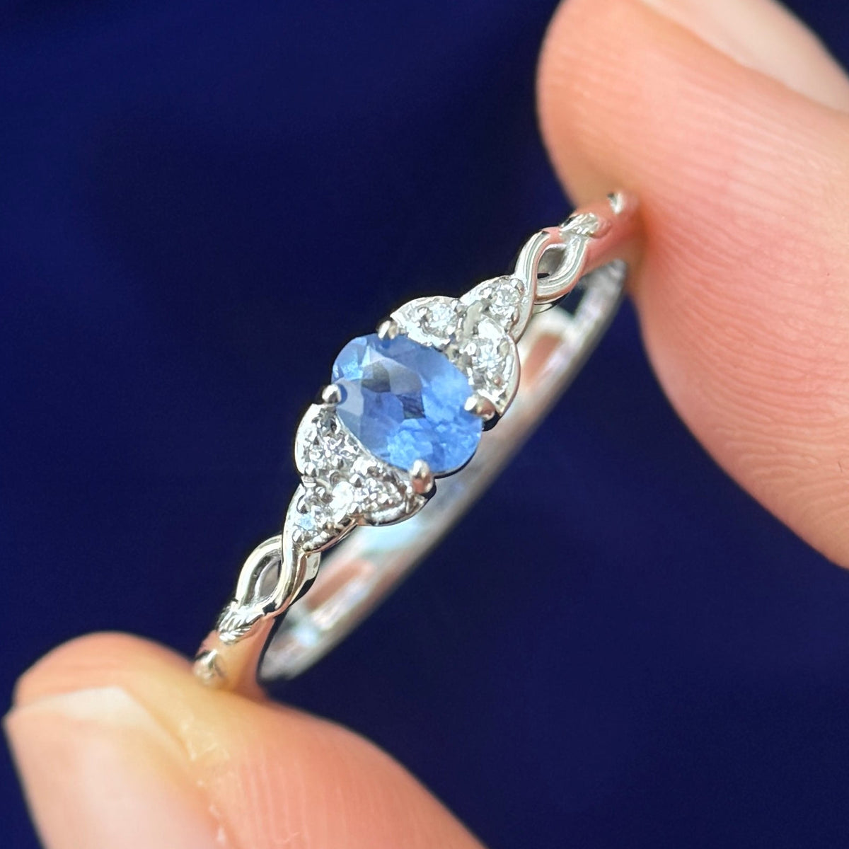 A model holding a 14k White Gold with Oval Natural Sapphire with Celtic Triquetras with 6 small diamonds on Branches Band Custom Ring