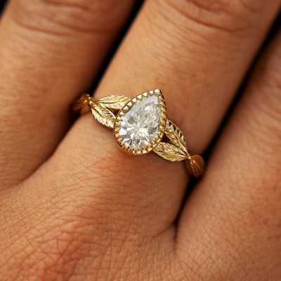 Close up view of a model's fingers wearing a 14k yellow gold Pear Lab Clear Diamond Leaves Ring