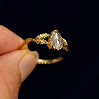 A model holding a Pear Salt and Pepper Diamond Leaves Ring tilted to show side of the ring