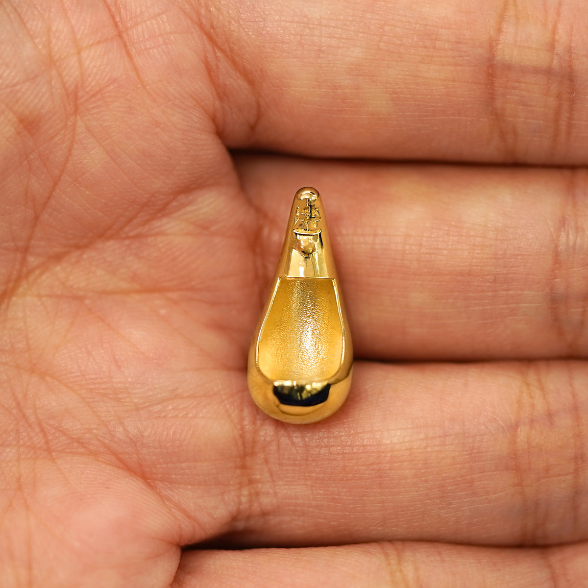 An Teardrop Puffy Earring laying facedown on a model's fingertips to show the underside view of the stud