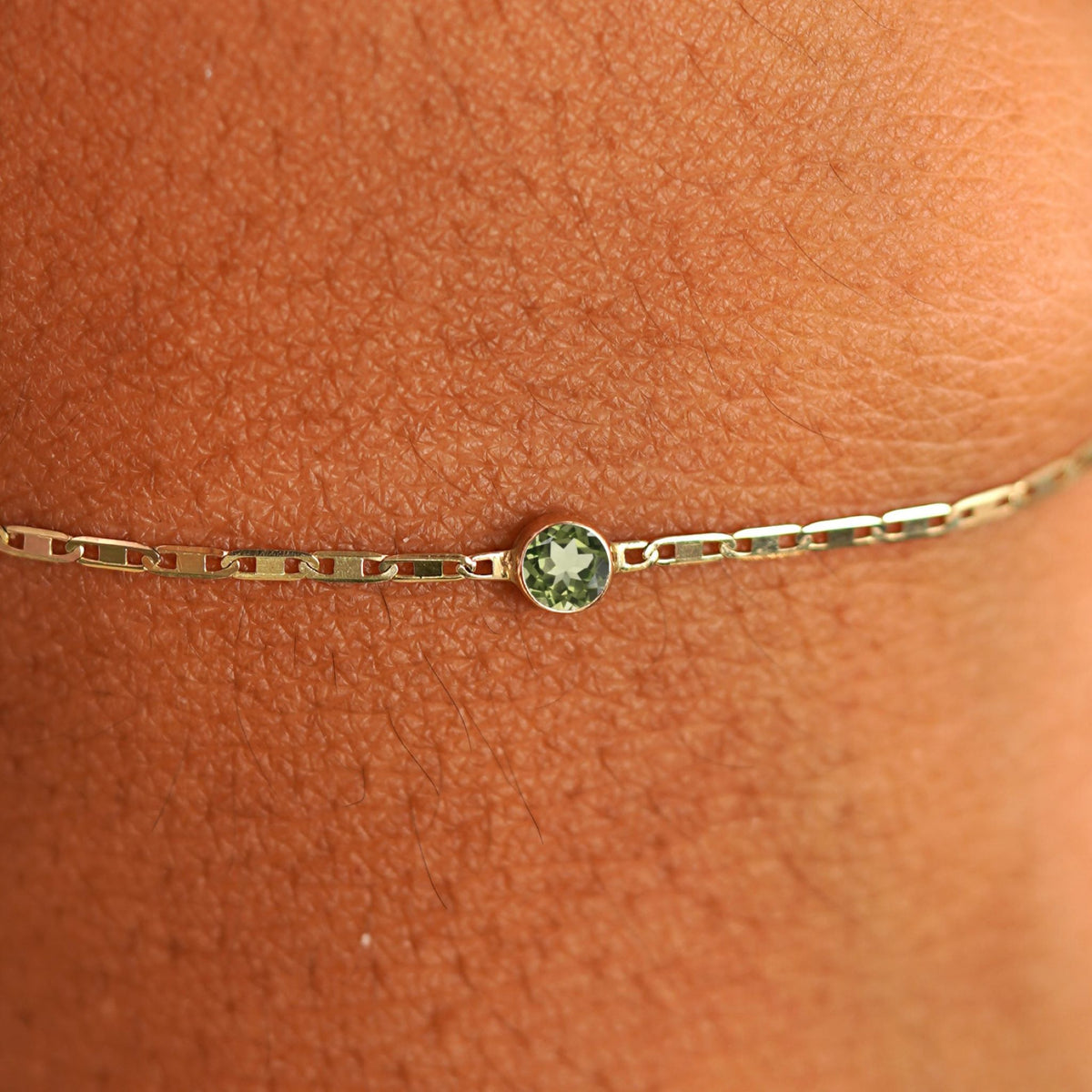 Close up view of a models wrist wearing 14k yellow gold Peridot Bracelet