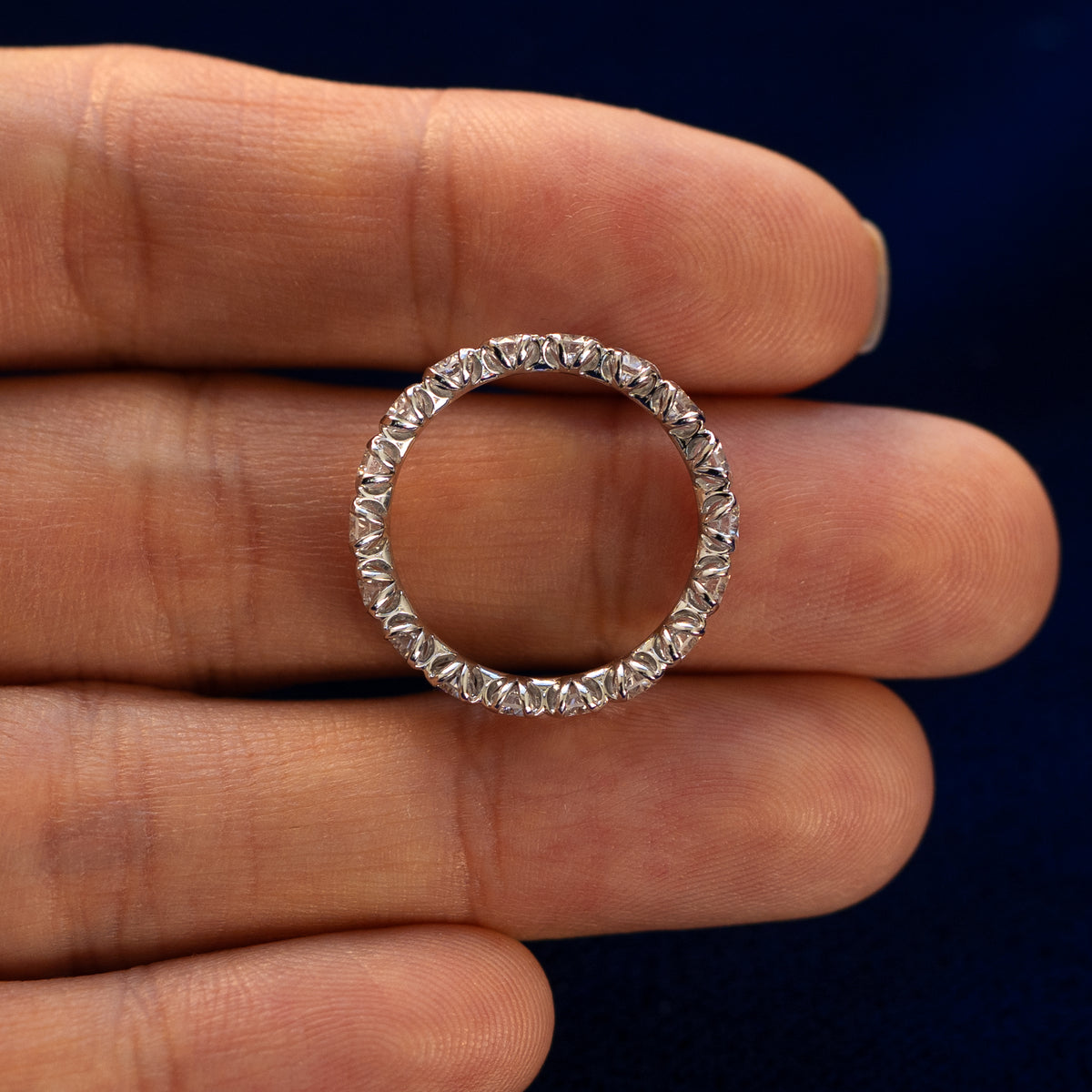 A Petal Set Diamond Eternity Band lying flat in a models hand to show the thickness of the Ring