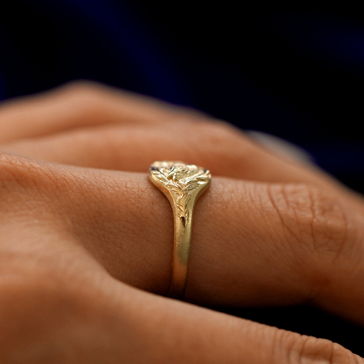 Side view of a Pine and Bird Ring on a model's finger to show the raised details