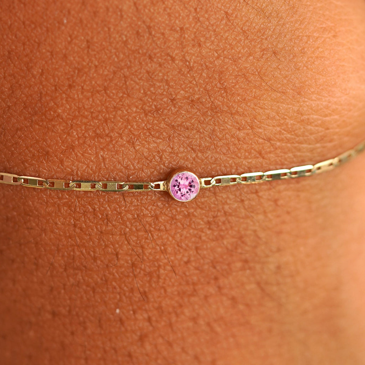 Close up view of a models wrist wearing 14k yellow gold Pink Sapphire Bracelet