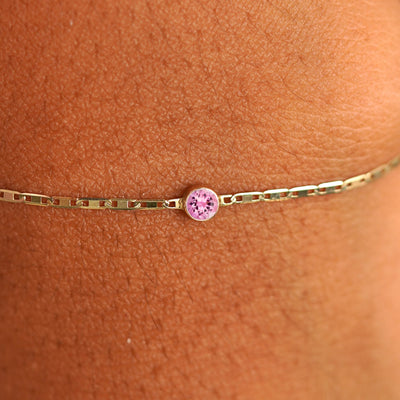 Close up view of a models wrist wearing 14k yellow gold Pink Sapphire Bracelet