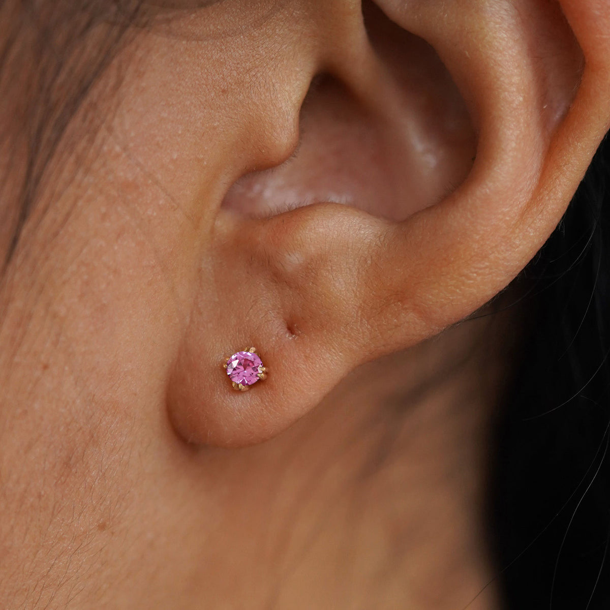 Close up view of a model's ear wearing a 14k yellow gold Onyx Earring