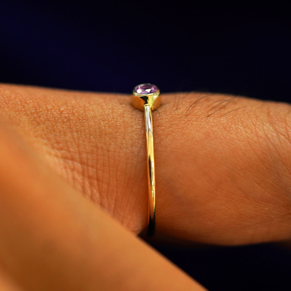 Side view of a Pink Sapphire Ring on a model's finger