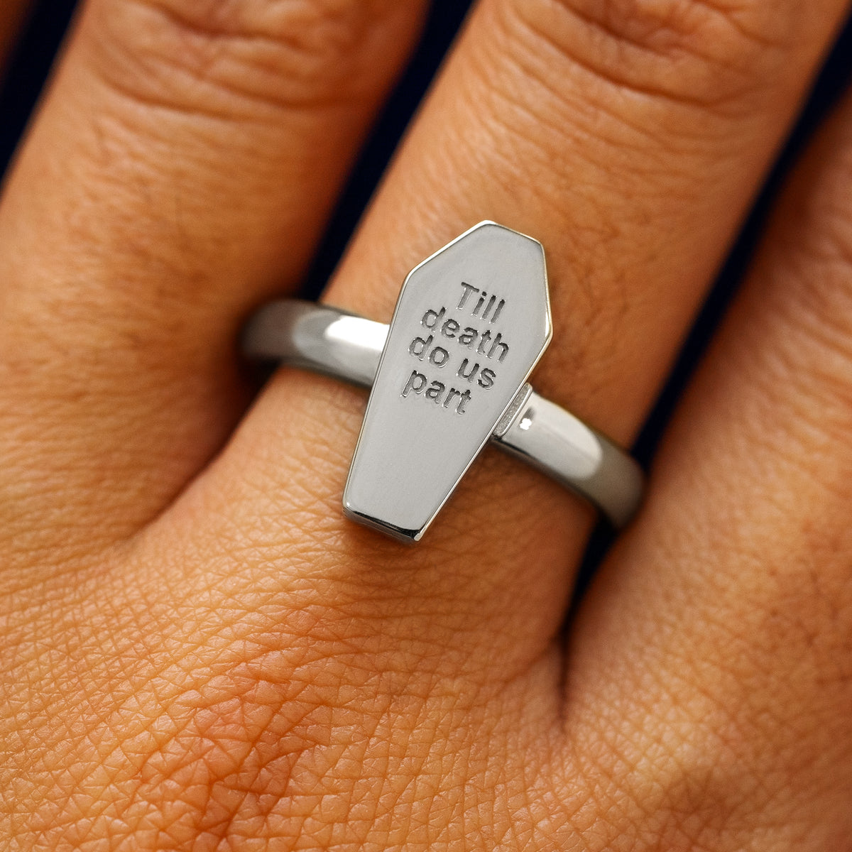 Close up view of a model's hand wearing a platinum gold Coffin Ring in the closed position