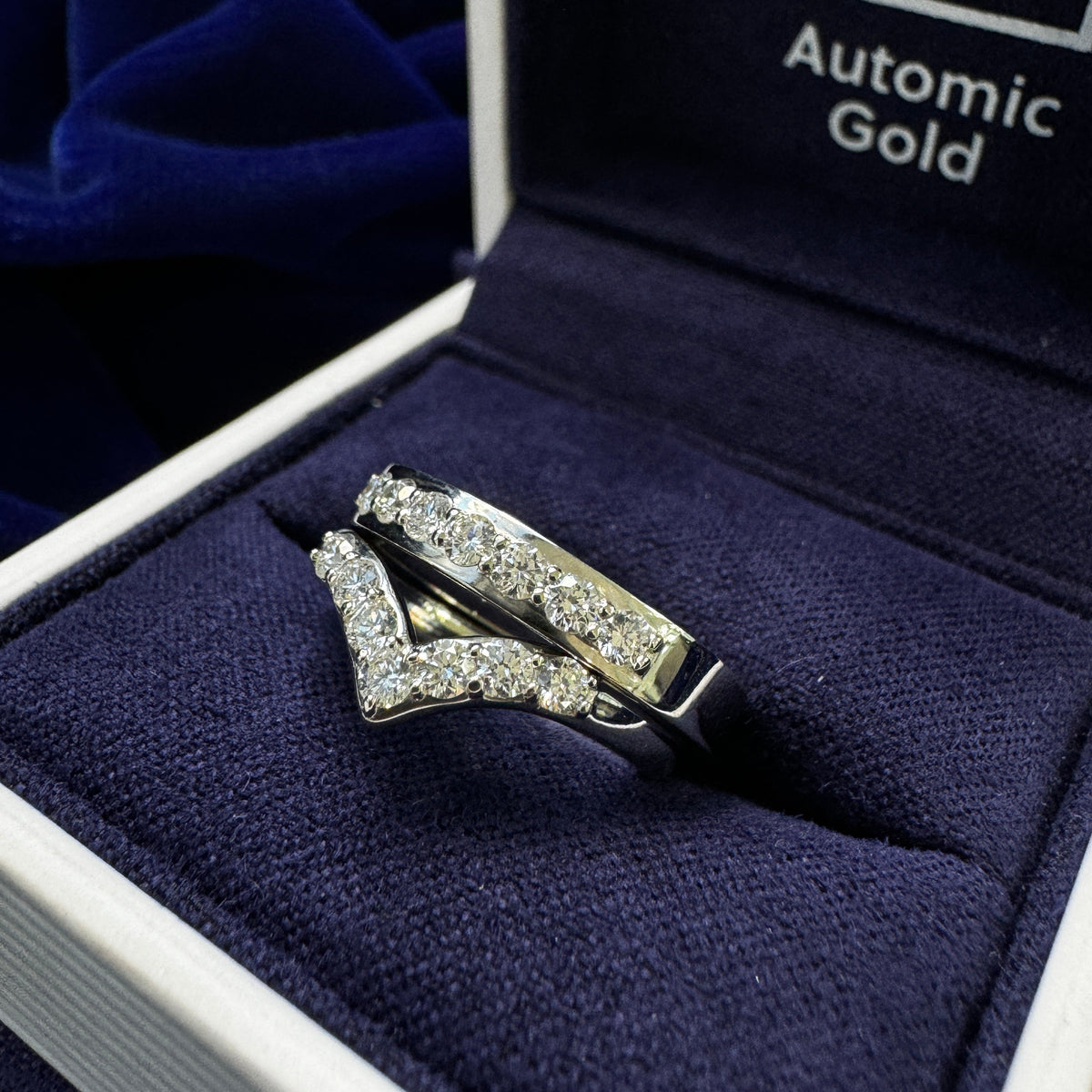 Two platinum round diamond rings one of each on chevron nesting band and one is on curvy mirror band