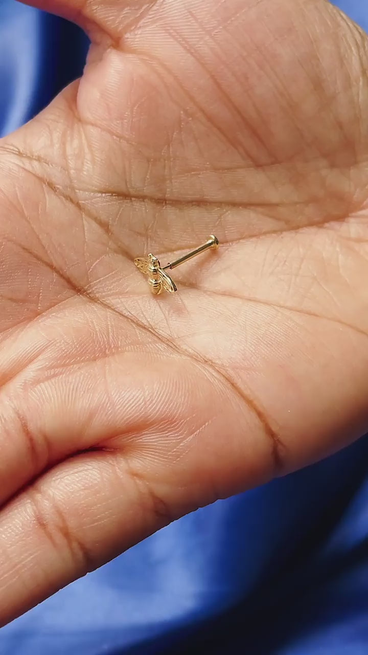 A model putting on a flatback by putting the backing in their ear first before the earring