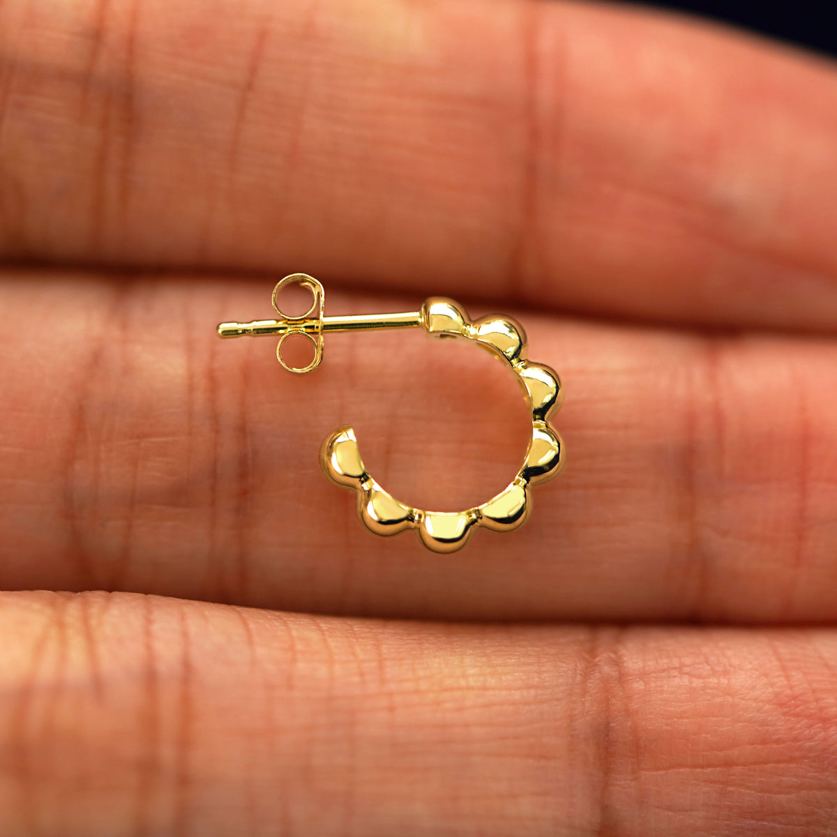 A Mini Puffy Beaded Hoop laying sideways on a model's fingertips to show the details of the post and the side of the hoop