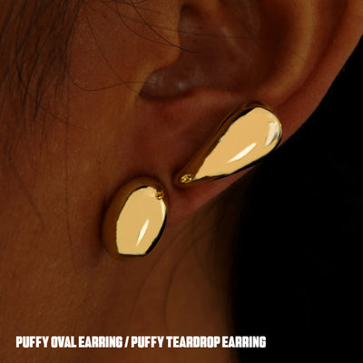 A model's ear with a yellow gold Oval Puffy and Teardrop Puffy Earring worn horizontally on two different lobe piercings