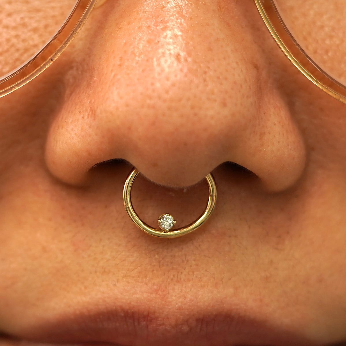 Close up view of a model's nose wearing a 14k yellow gold Raised Diamond Septum