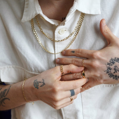 A model twisting a signet ring on their finger while wearing other Automic Gold jewelry