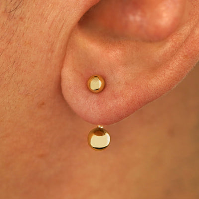 Close up view of a model's ear wearing a 14k yellow gold Large Curved Barbell through a lobe piercing