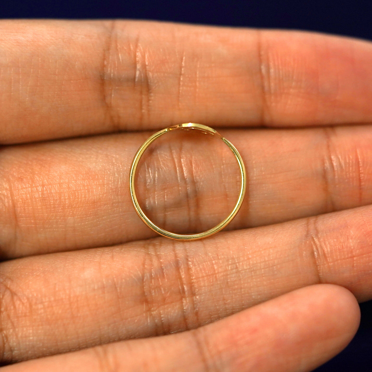 A yellow gold Smiley Face Ring in a model's hand showing the thickness of the band