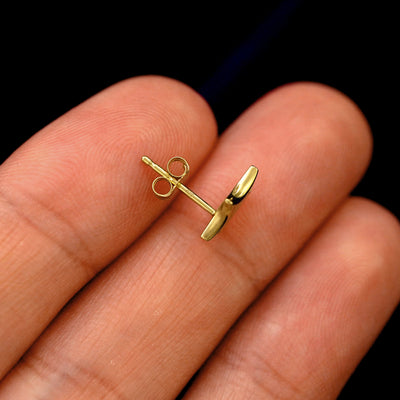 A 14k gold Sparkly Emoji Earring in a model's hand resting on its side with a standard pushback backing on its post