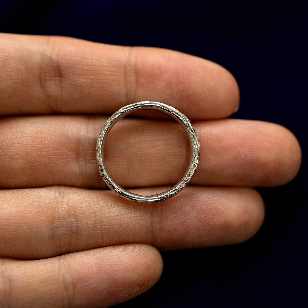 A baguette diamond raw band laying on a models fingertips to show the thickness of the ring