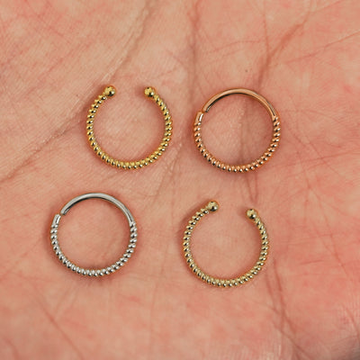 Four versions of the Rope Septum shown in options of yellow, white, rose and champagne gold in a model's palm
