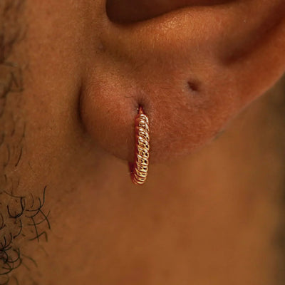 A model's ear wearing a 14k rose gold Small Rope Huggie Hoop Earring