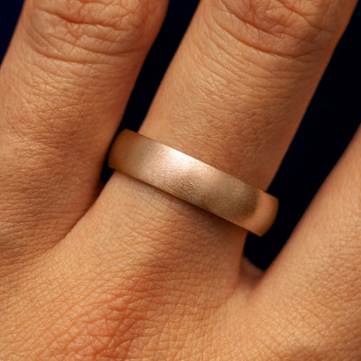 A models hand wearing a 14k rose gold curvy matte band