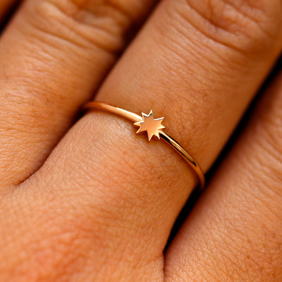 Close up view of a models fingers wearing a rose gold 8 pointed star ring