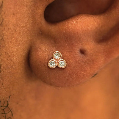 Close up view of a model's ear wearing a 14k rose gold Diamond Trio Earring