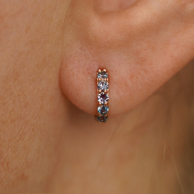 Close up view of a model's ear wearing a rose gold Small Alexandrite Huggie Hoop