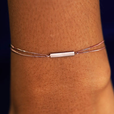 A model's wrist wearing a solid rose gold Bar Bracelet