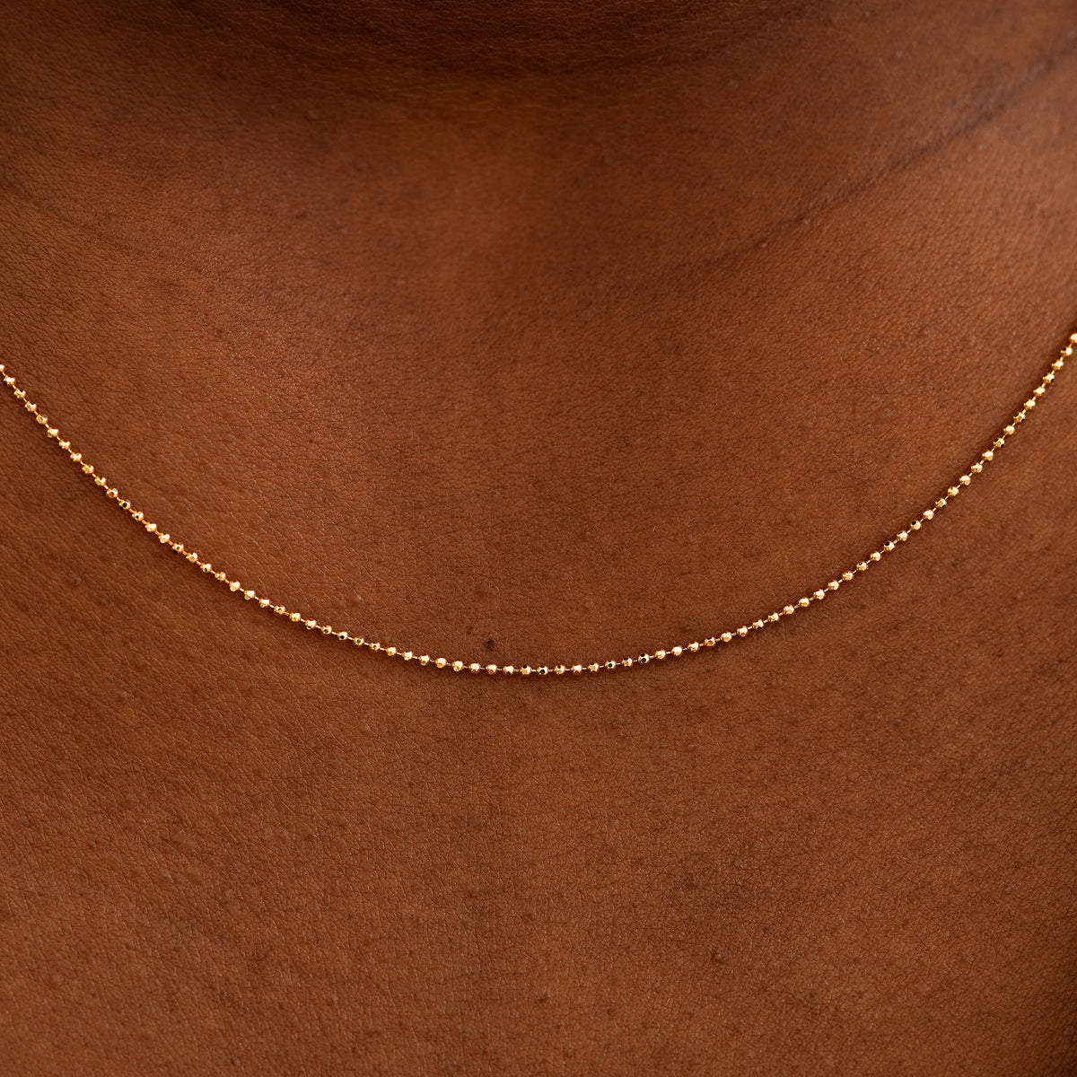 Close up view of a model's neck wearing a solid rose gold Bead Chain