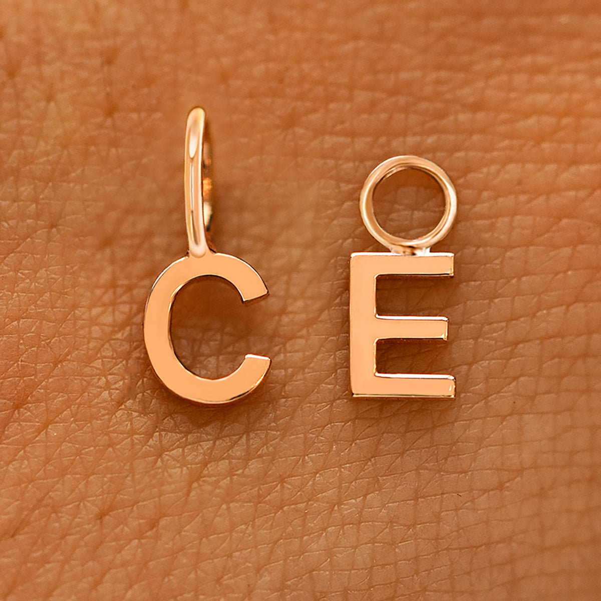 Two versions of the Block Initial Charm in the letters C and E showing For Chain and For Earring options in rose gold
