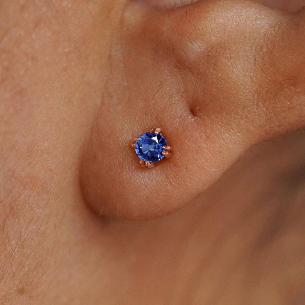 Close up view of a model's ear wearing a 14k rose gold Sapphire Earring