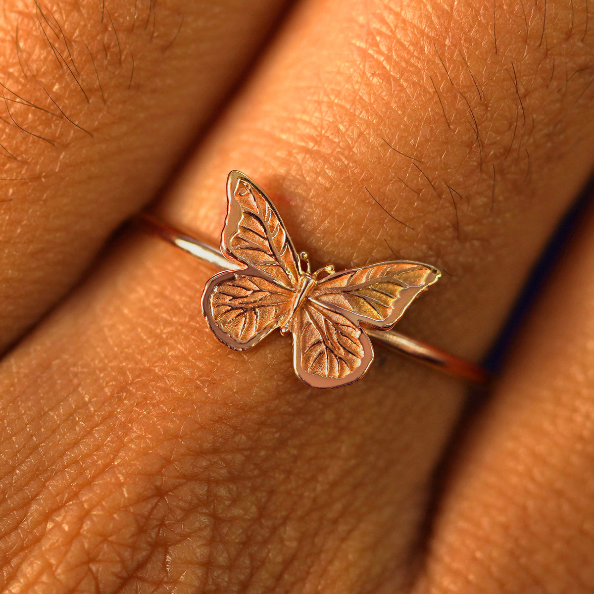 Close up view of a model's fingers wearing a rose gold Butterfly Ring