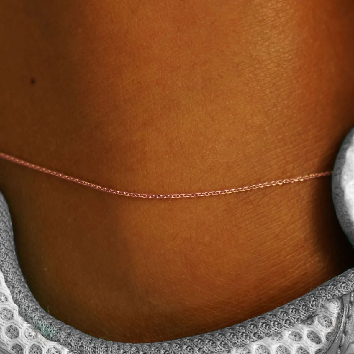 Close up view of a model's ankle wearing a rose gold Cable Anklet