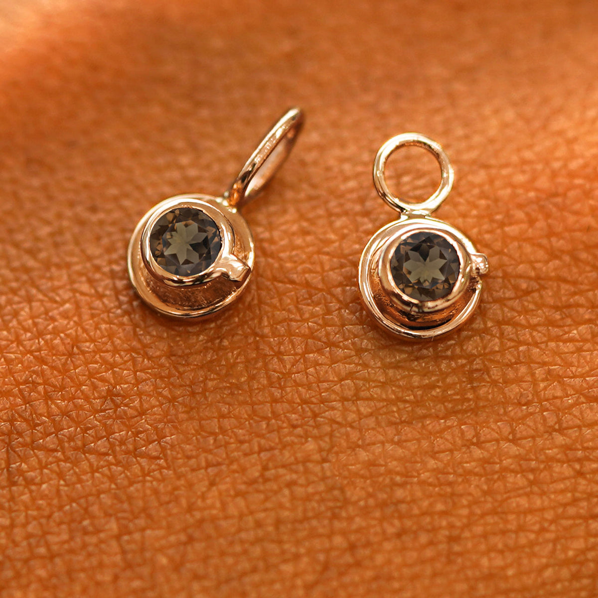 A solid rose gold coffee cup charm resting on a back of the model's hand
