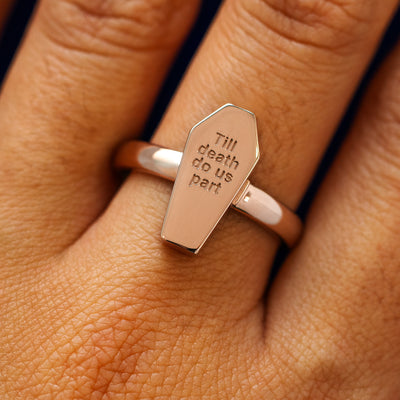 Close up view of a model's hand wearing a rose gold Coffin Ring in the closed position