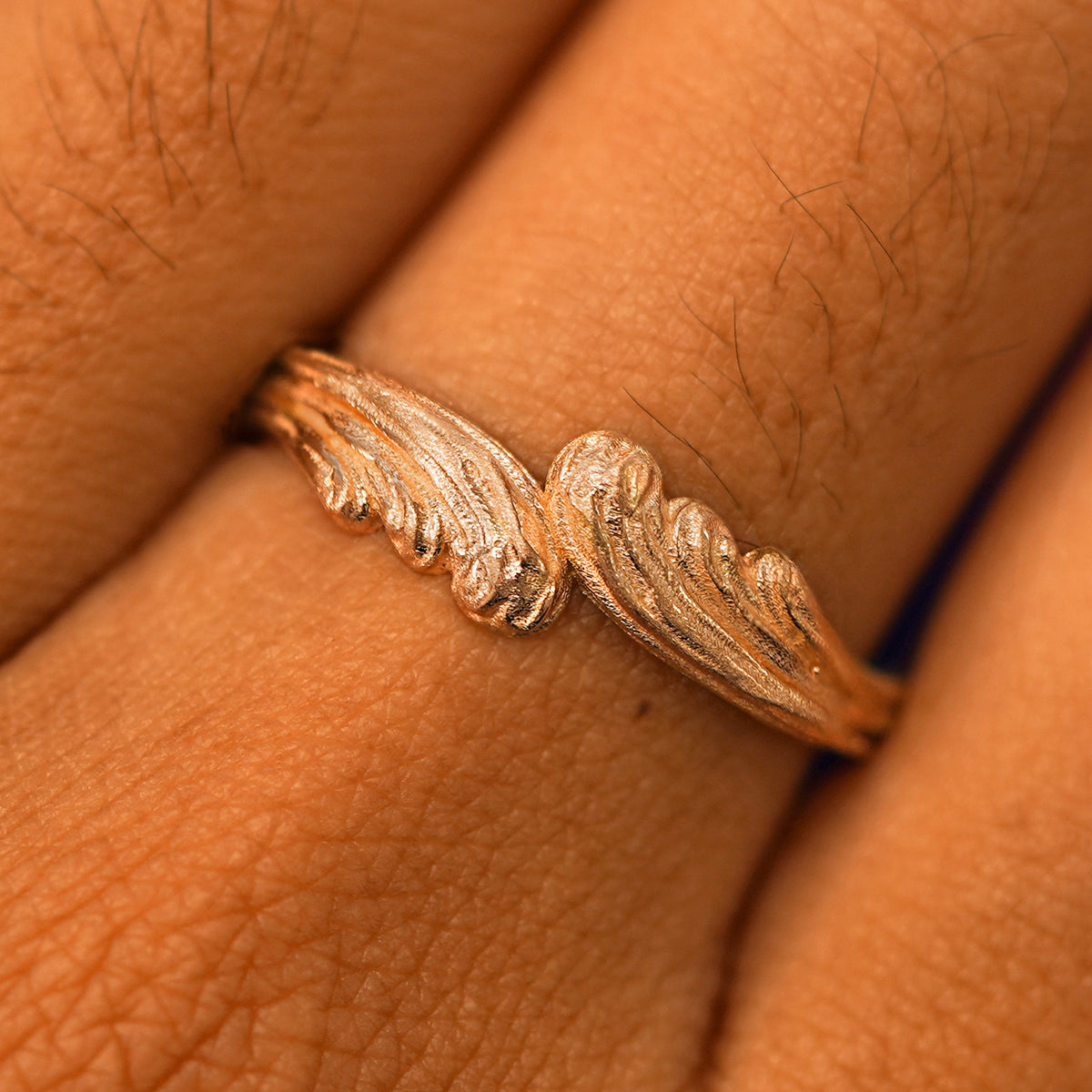 Close up view of a model's fingers wearing a 14k rose gold Crashing Waves Band